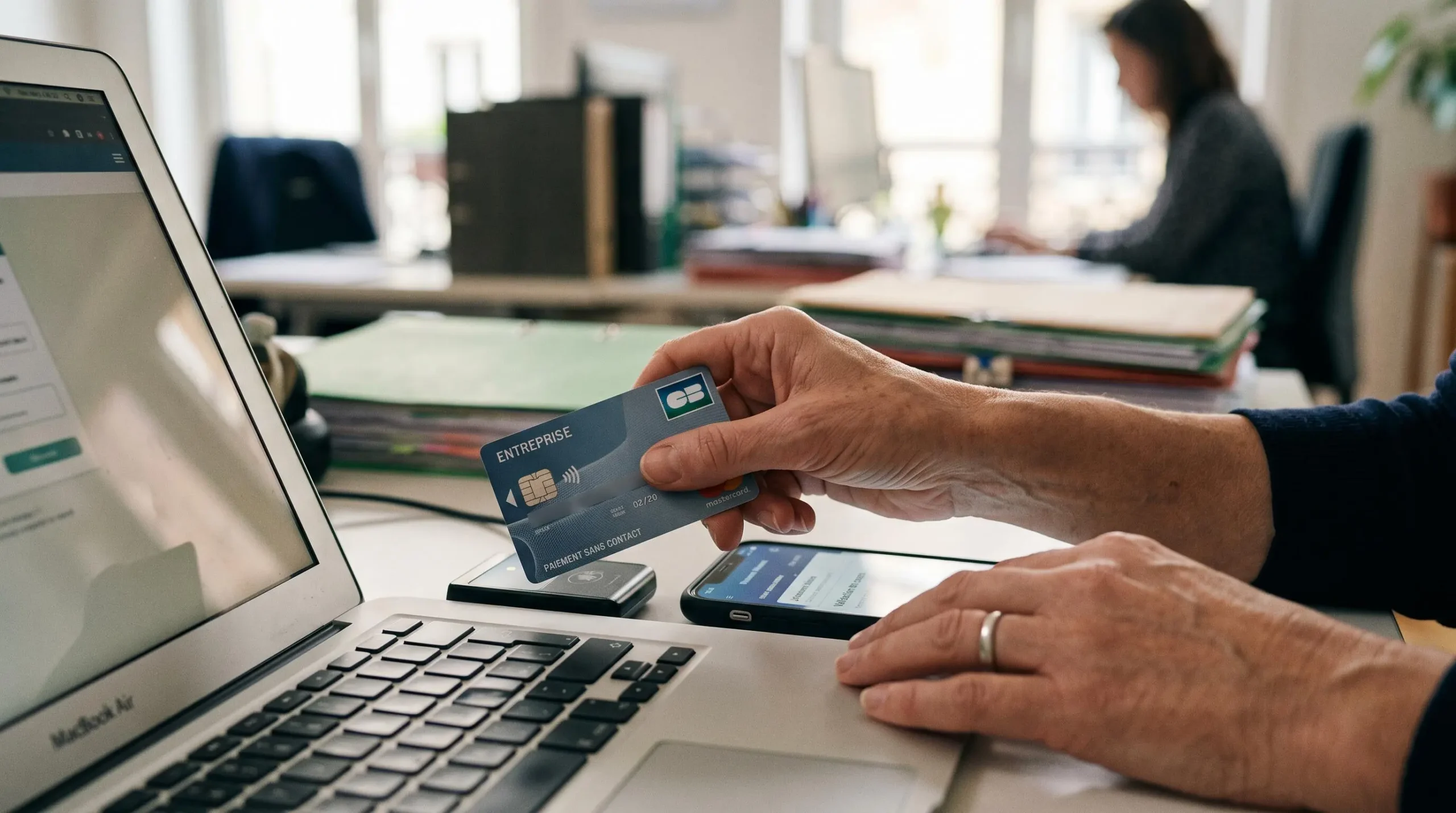 Main utilisant une carte bancaire professionnelle pour une opération liée à la gestion de la paie